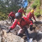 Adventurer ghyll scrambling through a hidden mountain stream in the Lake District near Keswick.